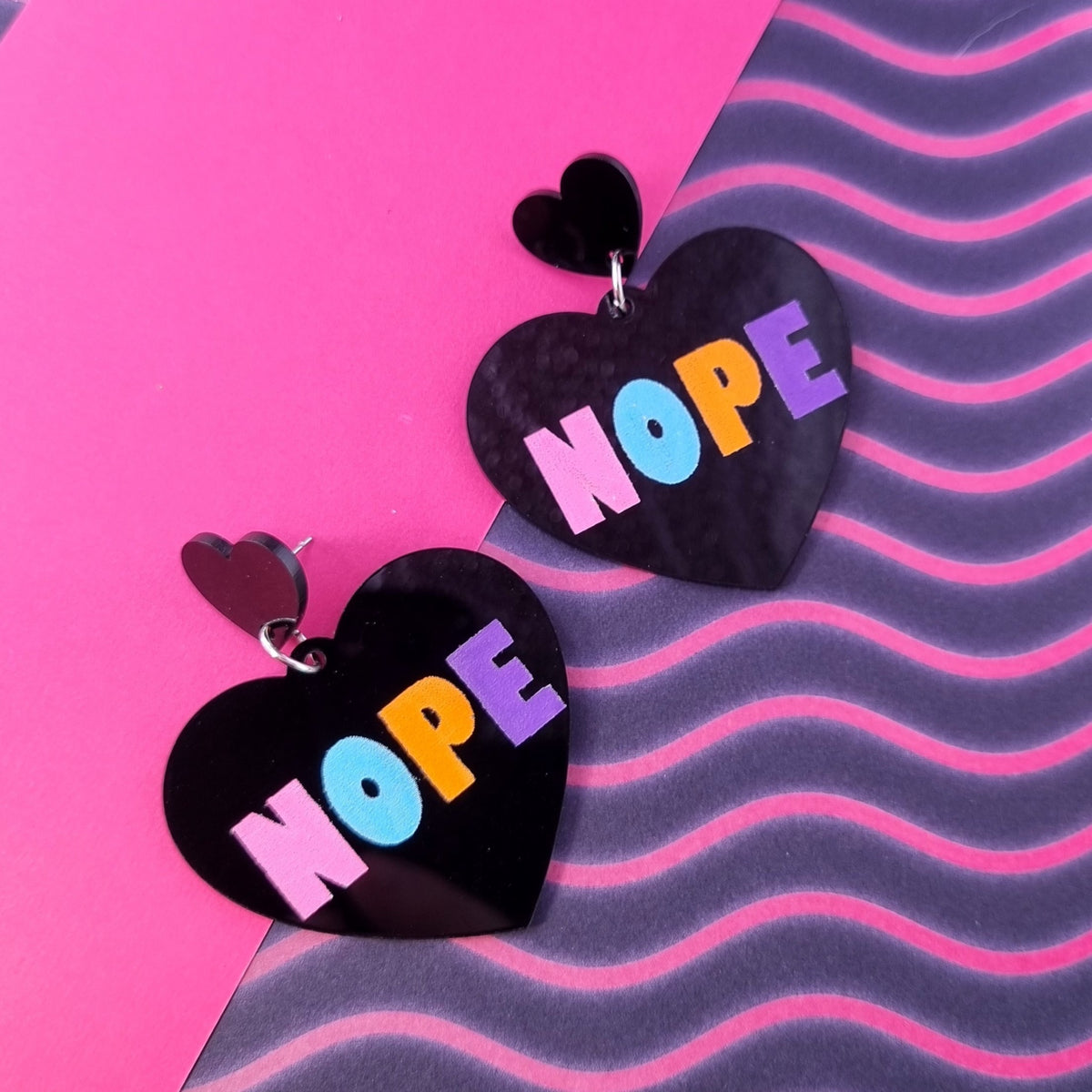 Black heart drop earrings with pastel multicolour NOPE lettering