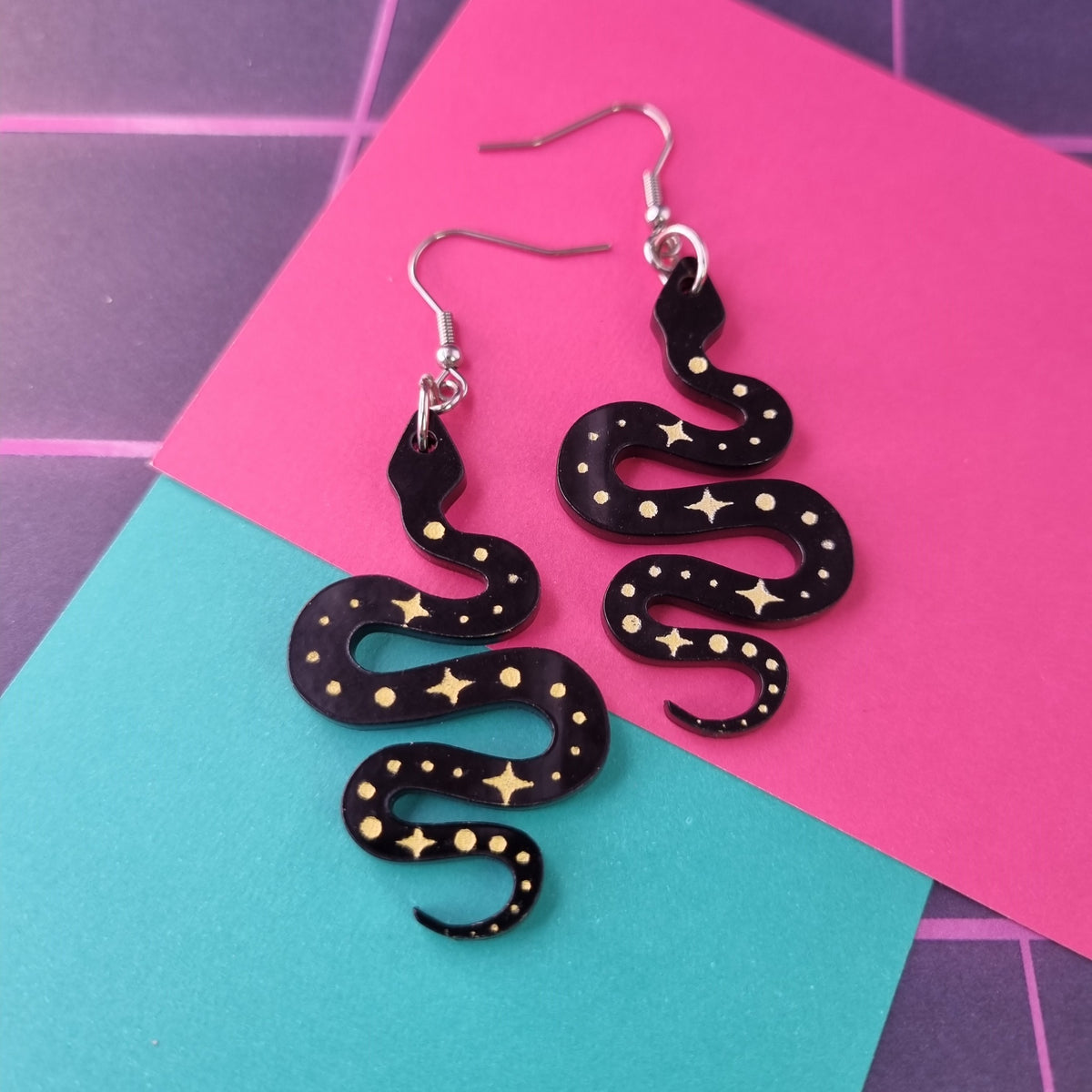Black acrylic snake earrings with gold stars and dots
