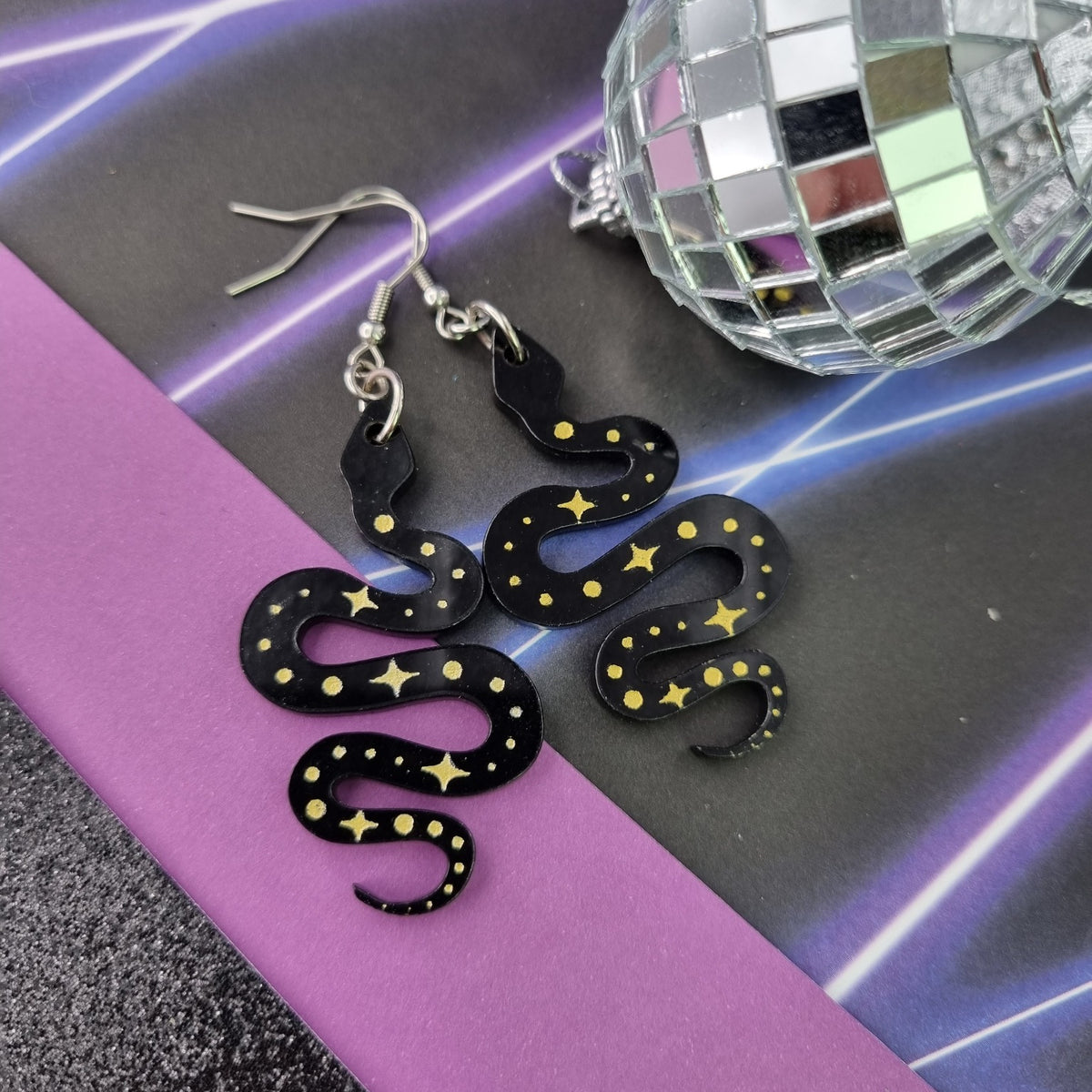 Black acrylic snake earrings with gold stars and dots, view 2