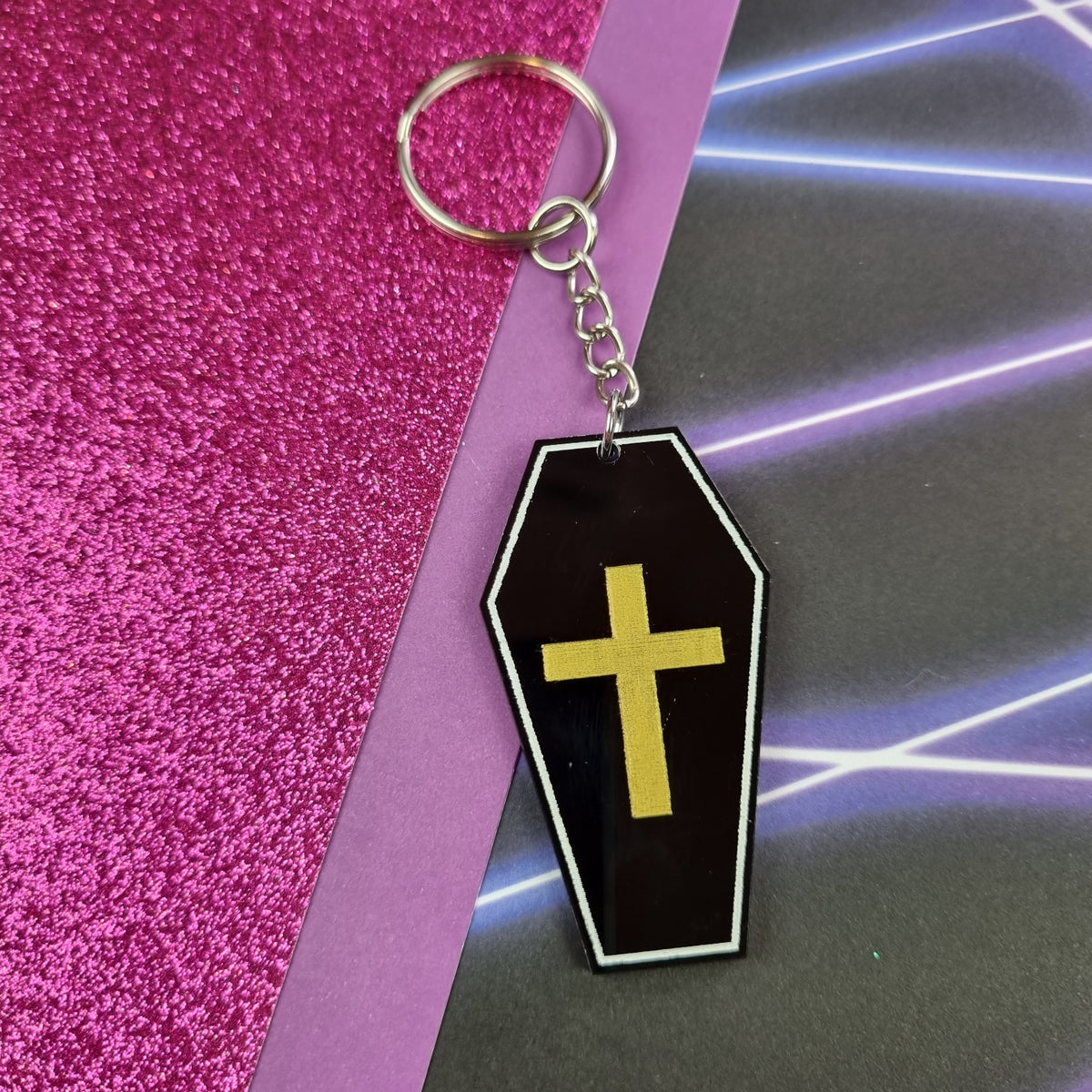 Black acrylic coffin keyring with white outline and gold cross, view 2