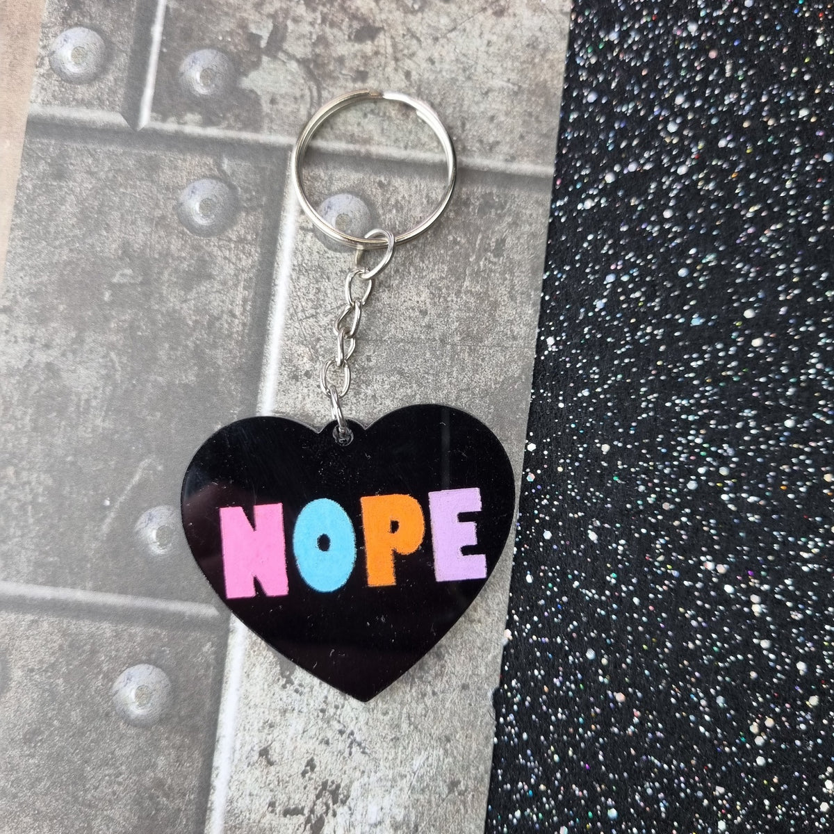 Black heart keyring with pastel multicolour NOPE lettering