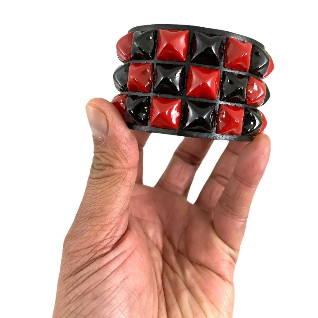 Three Pyramid Stud Checkered Snap Cuff, held in hand showing scale